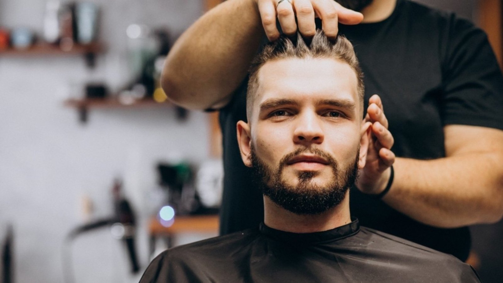 Hairdresser at a barber shop styling hair of a client